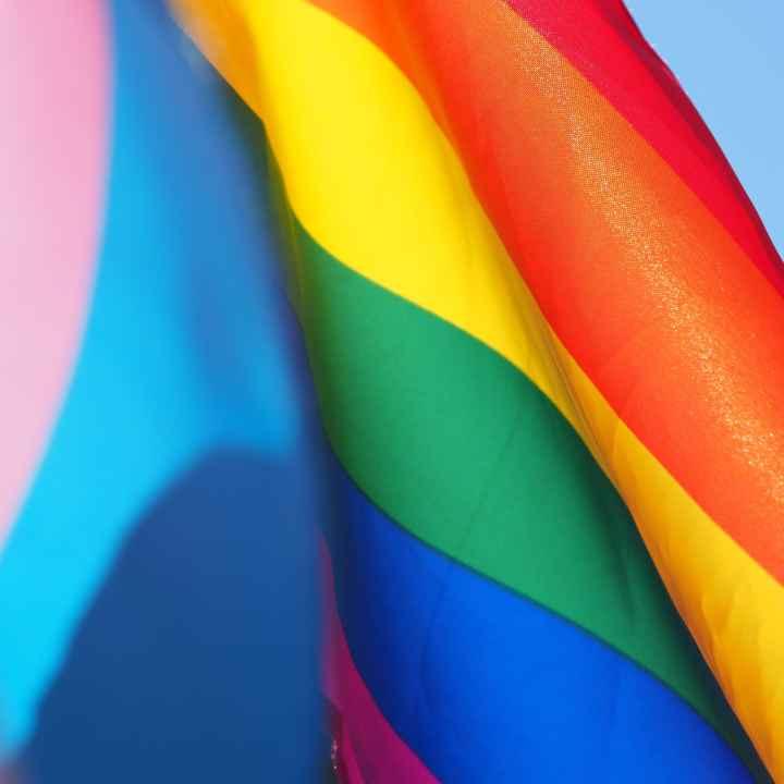 photo of rainbow flag waving against a light blue sky